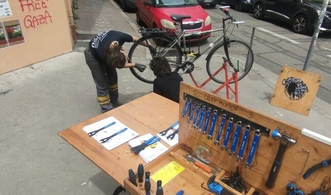 deux personnes réparant un vélo à coté de la remorque-atelier